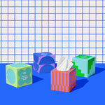Four boxes of of Who Gives a Crap recycled tissues against blue and white bathroom wall.