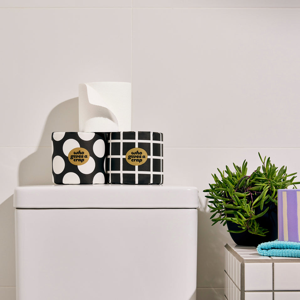 Three rolls of bamboo Who Gives a Crap toilet paper on display on top of toilet in home
