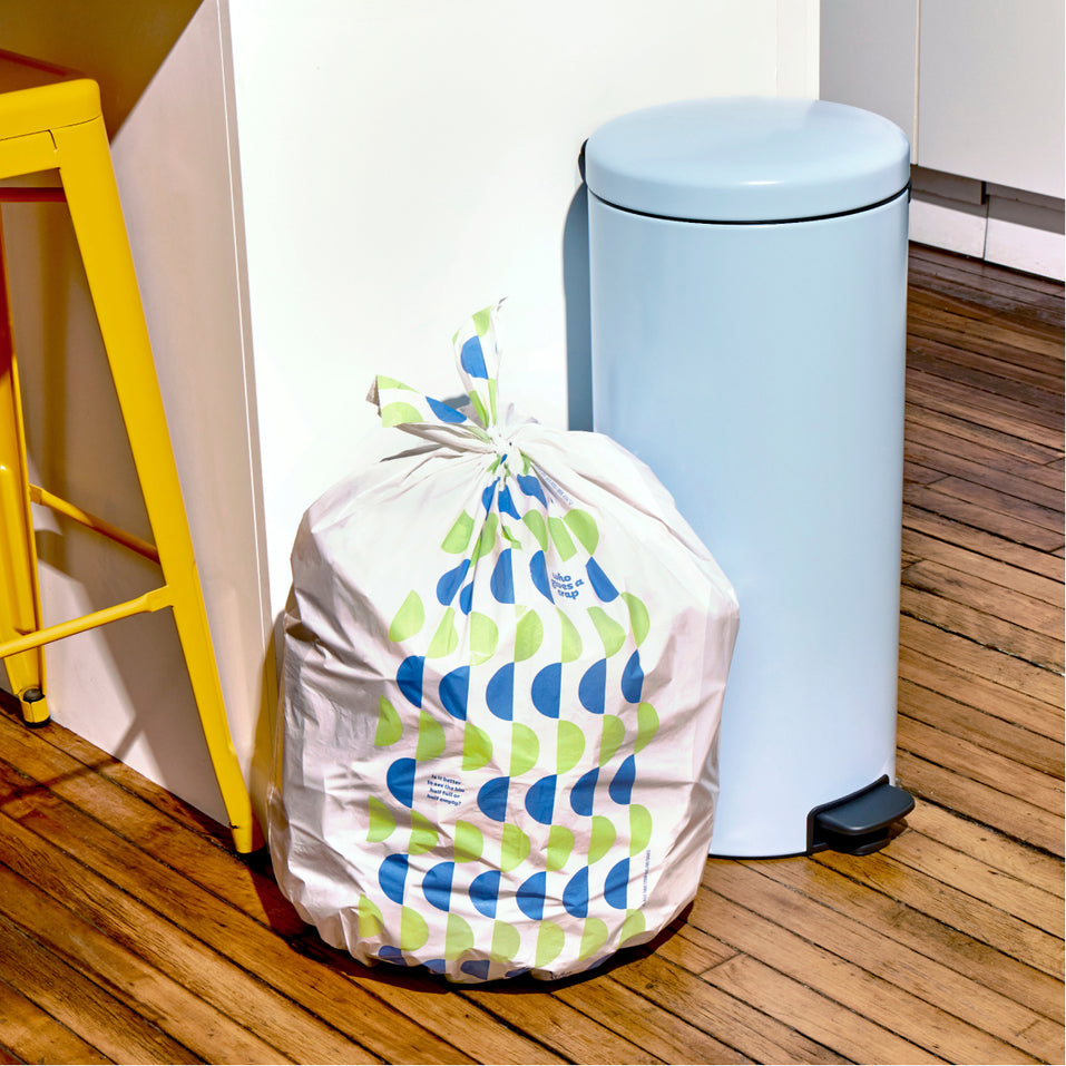 Who Gives a Crap large recycled garbage bag sits full next to kitchen bin.