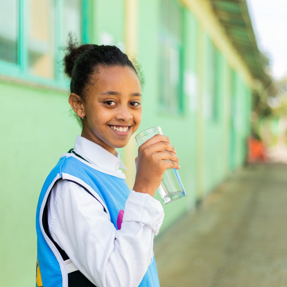 Young school girl holding a clean glass of water.